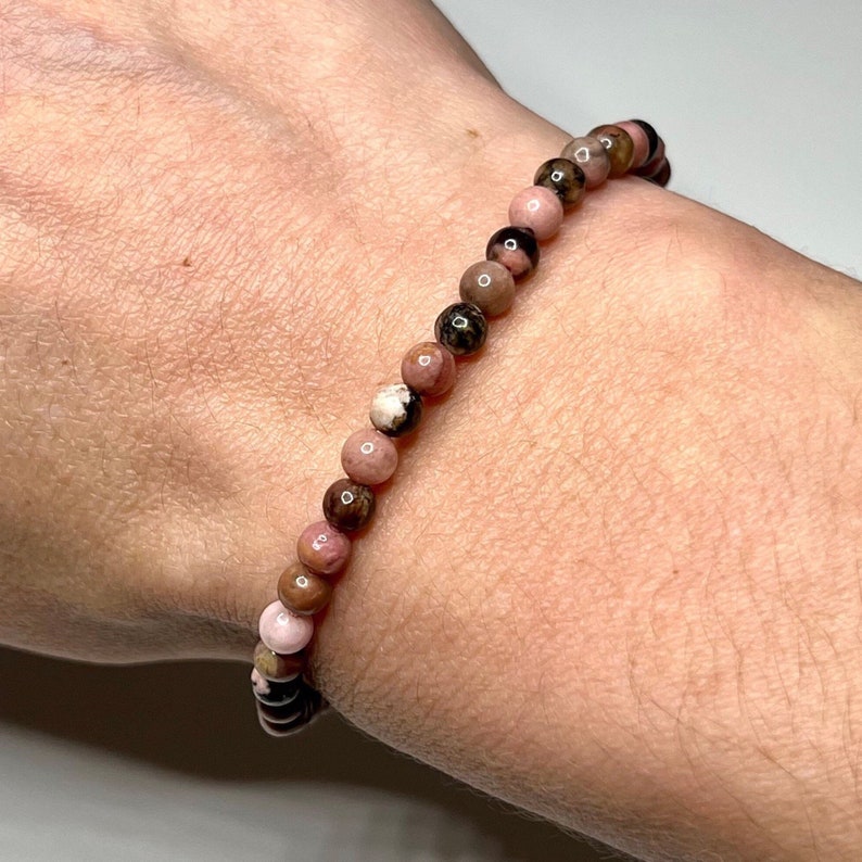 A pink, brown, and black beaded bracelet made of natural stones.