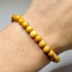A bracelet made of round, light yellow wooden beads.