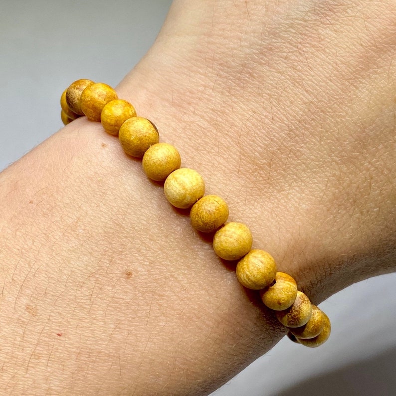A bracelet made of round, light yellow wooden beads.