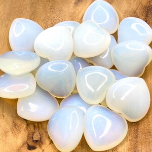 A collection of heart shaped blue and white opalite stones on a wooden surface.