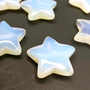 May include: A group of six iridescent white opal star-shaped stones on a black background.