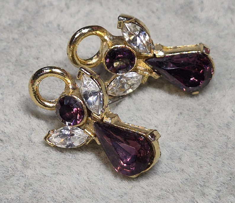 May include: A white ceramic mug with a black handle and the text "But First, Coffee" in a black, handwritten-style font. The mug is on a white surface.