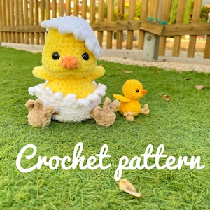 May include: A crochet pattern for a yellow chick emerging from a white egg, with a smaller yellow chick sitting beside it. The chicks are on a green grassy surface.