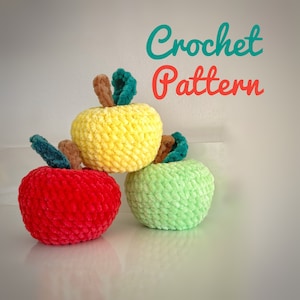Peut inclure: Trois pommes en crochet de couleur rouge, jaune et verte. Les pommes sont disposées en rangée, la pomme jaune au milieu. L'image comprend le texte "Crochet Pattern".