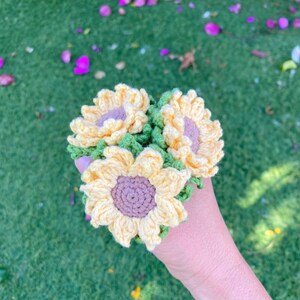May include: A bouquet of three crocheted sunflowers in yellow and green. The sunflowers have brown centers.