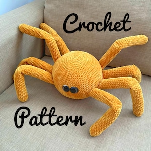 May include: A crocheted yellow spider with black eyes. The spider is lying on a light brown surface. The text "Crochet Pattern" is written below the spider.