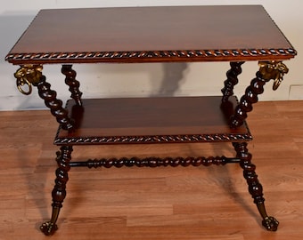May include: A dark brown, antique side table with a rectangular top and a lower shelf. The table features ornate, carved details, including twisted legs, rope-like trim, and lion head accents. The table's dimensions are approximately 30 inches long, 18 inches wide, and 28 inches high.