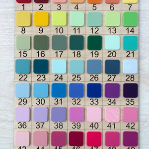 Puede incluir: Una carta de colores de madera con 49 muestras de colores numeradas. Las muestras est&aacute;n dispuestas en una cuadr&iacute;cula y muestran una variedad de colores, incluyendo rojos, naranjas, amarillos, verdes, azules, morados y rosas. Cada muestra es cuadrada.