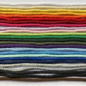Könnte beinhalten: Eine Sammlung von 20 verschiedenen farbigen Schnüren, die in einem Regenbogenmuster angeordnet sind. Die Schnüre sind aus einem weichen, strukturierten Material gefertigt und eignen sich perfekt für Bastelprojekte.