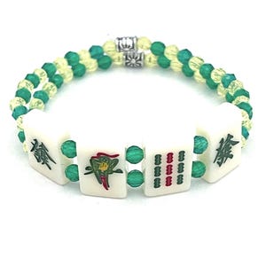 May include: A bracelet featuring four white rectangular mahjong tiles with black, green, and red character engravings, strung between alternating translucent green and pale yellow faceted beads, finished with two silver-toned metal spacer beads.