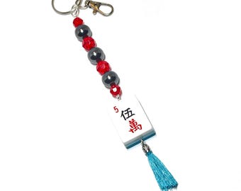 Llavero con ficha de Mahjong: Ficha auténtica con reverso azul brillante, cuentas negras, separadores de acrílico rojo, borla y clip para bolso.