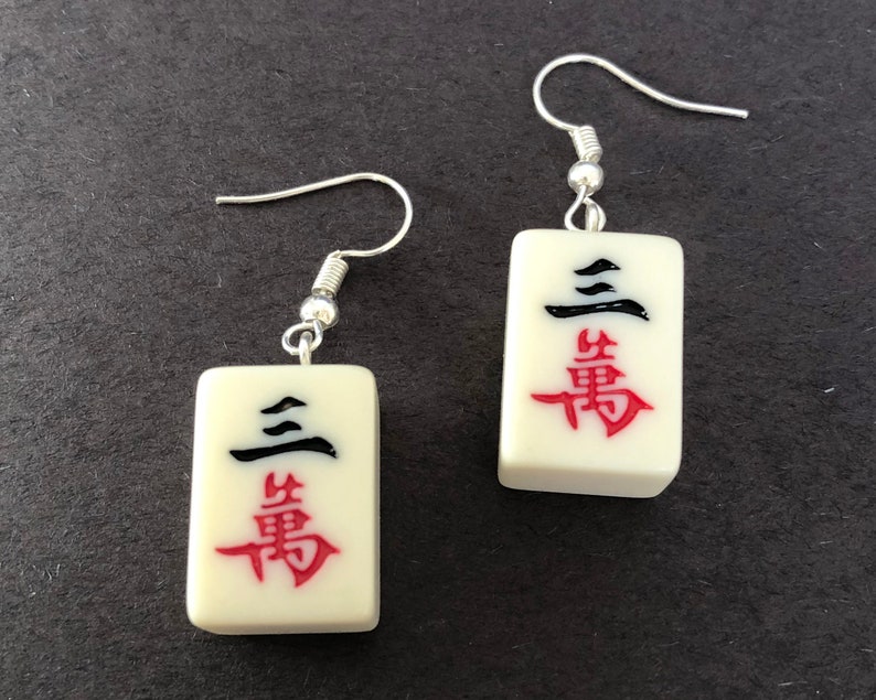 Miniature Mahjong Tile earrings hung on hypoallergenic stainless steel shepherds hooks. Choose from Craks, Dots, Bams, Winds, Dragons, or Flowers. Wow your Mahjong group when you show up wearing these earrings, created using tiles from a real Chinese travel set, which are smaller and slightly different than traditional Western set tiles. They also make perfect gifts.