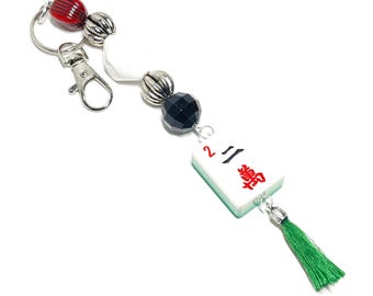 Llavero con ficha de mahjong: Ficha auténtica con reverso verde brillante, cuentas acrílicas, borla y clip para bolso.