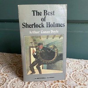 May include: A gray paperback book titled "The Best of Sherlock Holmes" by Arthur Conan Doyle. The cover features an illustration of a man in a dark suit holding a walking stick, with a large snake wrapped around him.