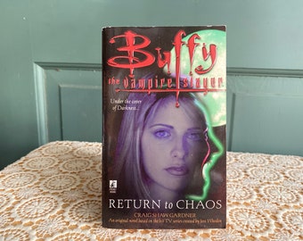 May include: A paperback book cover featuring a close-up of Buffy Summers, the main character from the TV series Buffy the Vampire Slayer. The cover is black with a red and white title, "Buffy the Vampire Slayer." The text "Under the cover of Darkness..." is printed in white below the title. The book title, "Return to Chaos" is printed in white on a black background at the bottom of the cover. The author, "Craig Shaw Gardner" is printed in white below the book title. The text "An original novel based on the hit TV series created by Joss Whedon" is printed in white below the author's name.