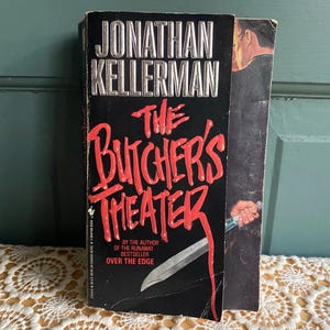May include: A paperback book titled "The Butcher's Theater" by Jonathan Kellerman. The title is in large, red, stylized letters against a black background. A silver knife is featured on the cover. The book is a thriller.