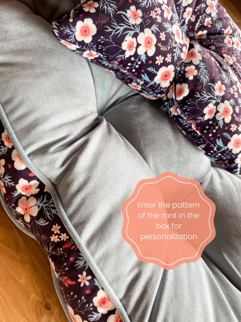 May include: A light blue floor cushion with a floral pattern border. The cushion has a tufted design and is made of soft fabric. A separate floral patterned pillow is on top of the cushion. The text "Enter the pattern of the rant in the box for personalization" is on a pink circle.