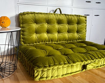Könnte beinhalten: Ein großes, grünes Samt-Bodenkissen mit gestepptem Design. Das Kissen ist in der Mitte gefaltet, um eine Sofa-ähnliche Form zu erzeugen.