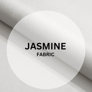Può includere: Tessuto bianco con il testo "JASMINE FABRIC" in un cerchio.