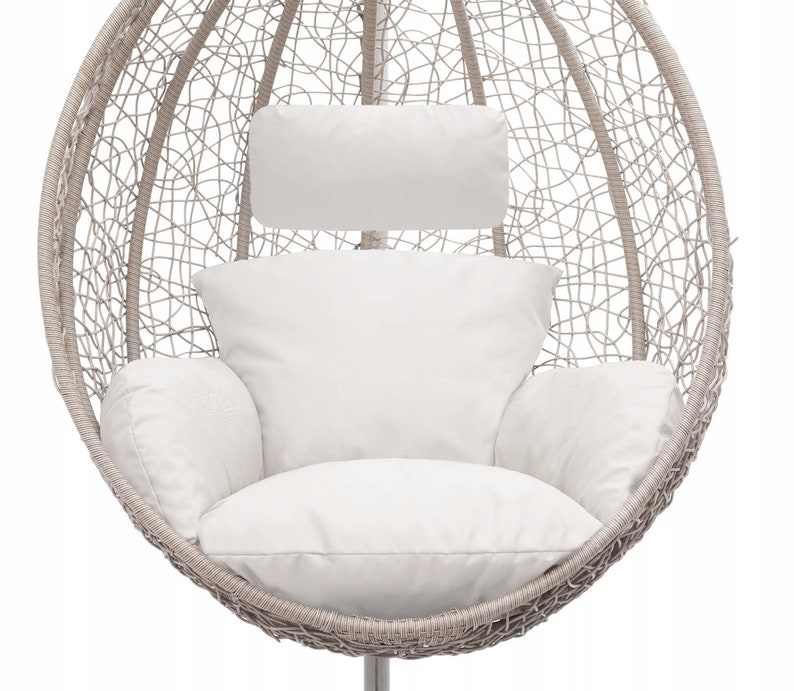 May include: A white wicker egg-shaped hanging chair with a white cushion and a white headrest. The chair is suspended from the ceiling by a metal chain.