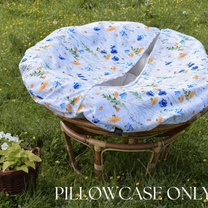 May include: A white and blue floral patterned chair cushion cover with a  "PILLOWCASE ONLY" text overlay. The cushion cover is on a round, wicker chair.