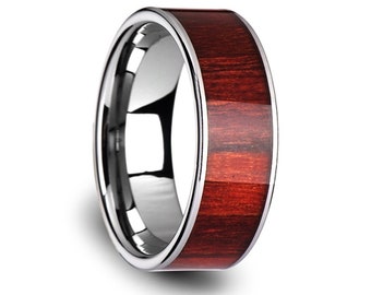 May include: A polished silver ring with a wide band of reddish-brown wood grain. The ring has a smooth, reflective surface and a modern design. The wood grain is visible and adds a natural element to the jewelry.