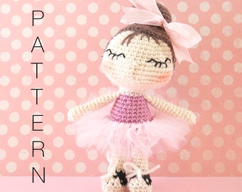 May include: A crocheted ballerina doll with a pink tutu, white shoes, and a pink bow in her hair. The doll is standing on a pink background with white polka dots.
