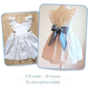 Boho flower girl dress with flutter sleeves. Girls pinafore dress with big bow sash. Simple white cotton sundress with dusty blue bow. UK