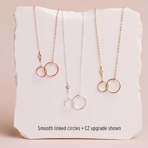 three necklaces with smooth linked circles, each with a different color of chain.