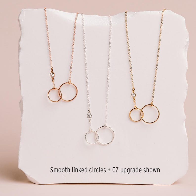 three necklaces with smooth linked circles, each with a different color of chain.