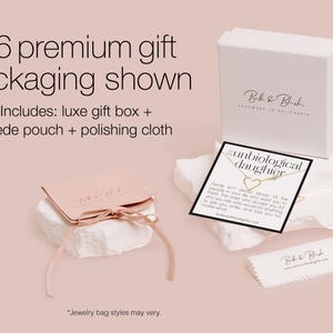 The image is an advertisement for a premium gift packaging service. It features a white box with a gold label, a pink gift bag, and a white cloth. The text on the image provides details about the premium gift packaging, including a luxury gift box, a suede pouch, and a polishing cloth. The image also includes a note about jewelry bag styles and a caution about avoiding redundancy and vague wording.