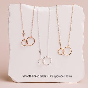 three necklaces with smooth linked circles, each with a different color of chain.