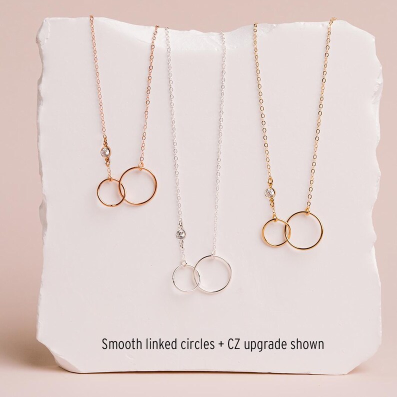 three necklaces with smooth linked circles, each with a different color of chain.