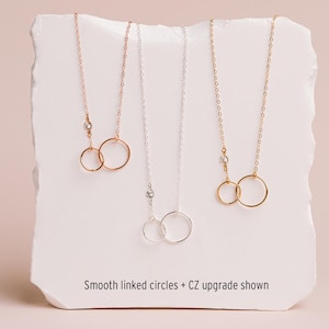 three necklaces with smooth linked circles, each with a different color of chain.