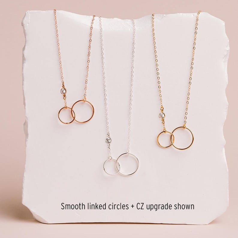 three necklaces with smooth linked circles, each with a different color of chain.
