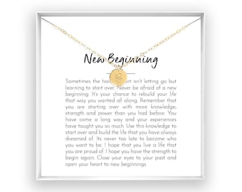 May include: A gold-toned necklace featuring a small circular pendant engraved with the letter B. The necklace is displayed on a white card printed with the text New Beginning and a paragraph of inspirational text about starting over in life.