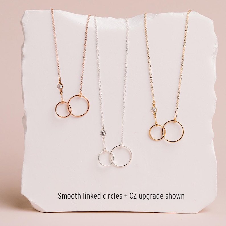 three necklaces with smooth linked circles, each with a different color of chain.