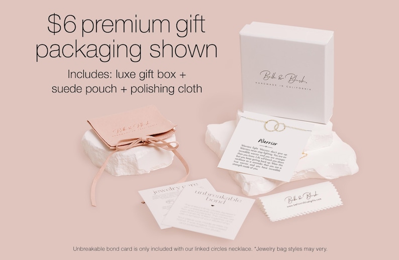 a premium gift packaging for a necklace, including a luxury gift box, a suede pouch, and a polishing cloth. The packaging is presented on a light pink background, and there is a note indicating that an Unbreakable Bond card is included with the necklace.