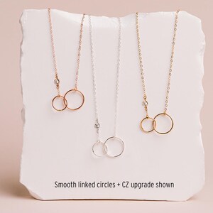 three necklaces with smooth linked circles, each with a different color of chain.