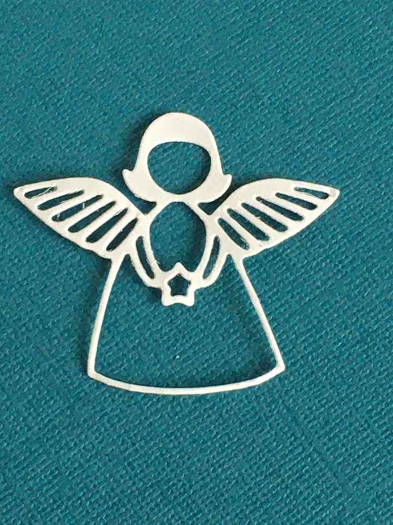 Pode incluir: Adorno de anjo de metal branco com asas e uma estrela no centro. O anjo &eacute; recortado no metal e tem um design simples.