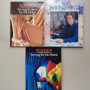 May include: Three sewing books are displayed, featuring the Singer brand. The top left book is titled "Sewing Projects for the Home." The top right book is "501 Sewing Hints." The bottom book is also "Sewing for the Home."