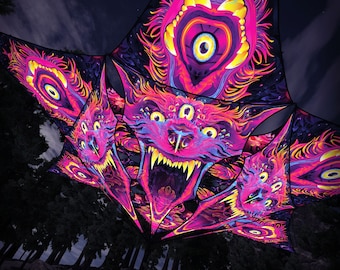 May include: A set of four colorful fabric panels with a psychedelic design featuring a multi-eyed creature with a large mouth and teeth. The panels are hanging from a tree branch in a forest setting.