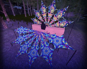 Puede incluir: Una gran estructura de toldo de tela de varios paneles con patrones psicodélicos vibrantes en tonos azul, morado, amarillo y rosa. El diseño incluye motivos complejos tipo mandala y rostros estilizados, sostenidos por postes negros sobre una base rosa claro.