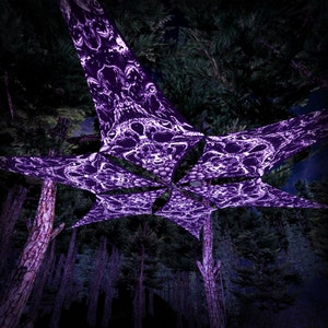 May include: A purple and white patterned canopy hanging between trees in a dark forest. The canopy is made of a fabric with a skull design.