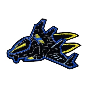 Könnte beinhalten: Schwarzer gestickter Aufnäher eines futuristischen Jets mit gelben und blauen Akzenten. Der Jet hat zwei Nachbrenner.