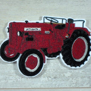 Könnte beinhalten: Roter gestickter Aufnäher eines roten Vintage-Traktors McCormick Farmall Super A mit schwarzen Reifen und Rädern.