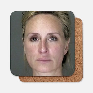 May include: A close-up portrait of a woman with blonde hair. She is looking directly at the camera with a neutral expression. Her face is pale and her eyes are blue.