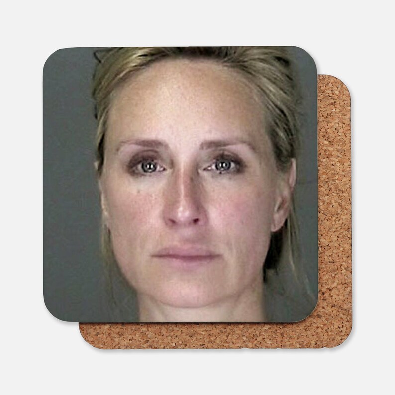 May include: A close-up portrait of a woman with blonde hair. She is looking directly at the camera with a neutral expression. Her face is pale and her eyes are blue.