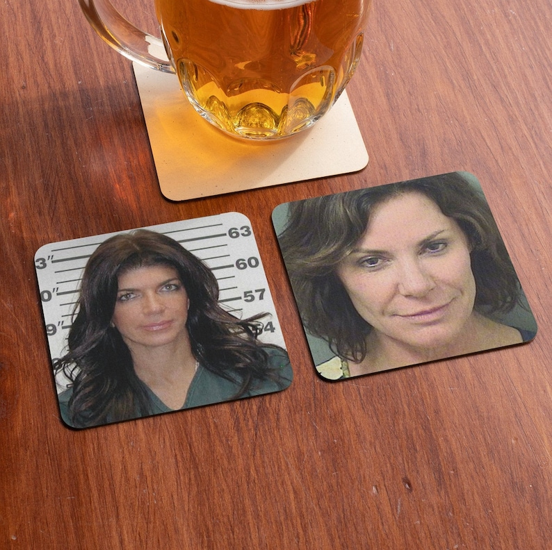 May include: Two square coasters featuring mugshot-style images of women. The coasters are placed on a wooden surface. One coaster displays a mugshot of a woman with dark hair against a white background with a height chart. The other coaster shows a mugshot of a woman with dark hair against a white background.