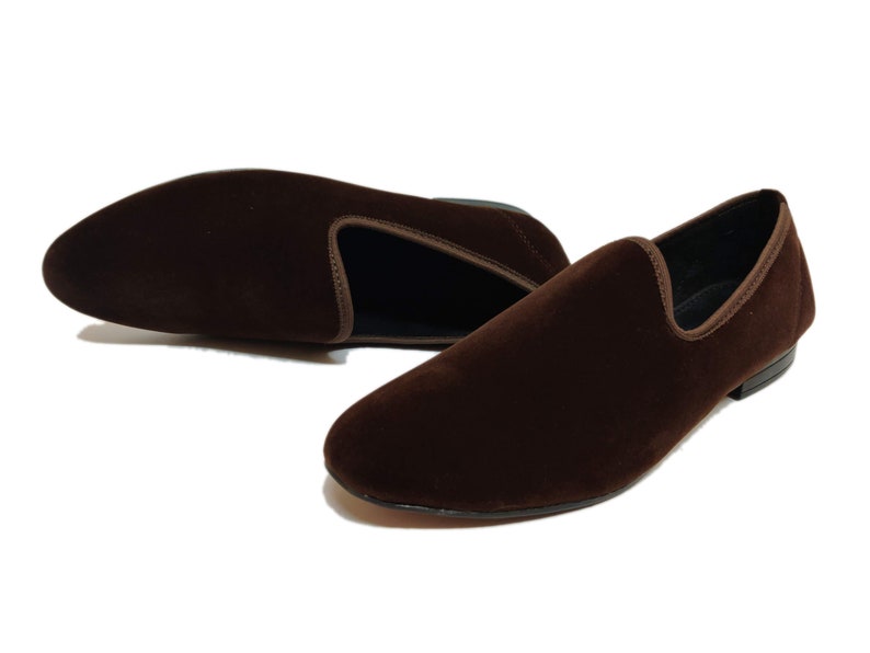 May include: A pair of brown velvet loafers. The loafers have a pointed toe and a slip-on design.